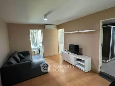 Modern living room with cozy sofa and TV unit, adjacent to dining area and bathroom.