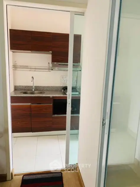 Modern compact kitchen with sleek wooden cabinets and sliding glass door