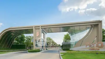 Modern gated entrance of luxury residential community with lush greenery and contemporary design.