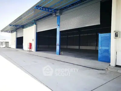 Spacious industrial warehouse with open roller doors and ample loading space.