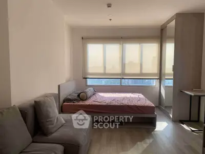 Modern bedroom with large windows and cozy seating area in a stylish apartment.