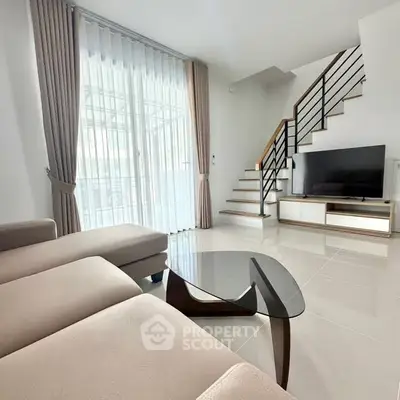 Spacious modern living room with elegant staircase and large windows