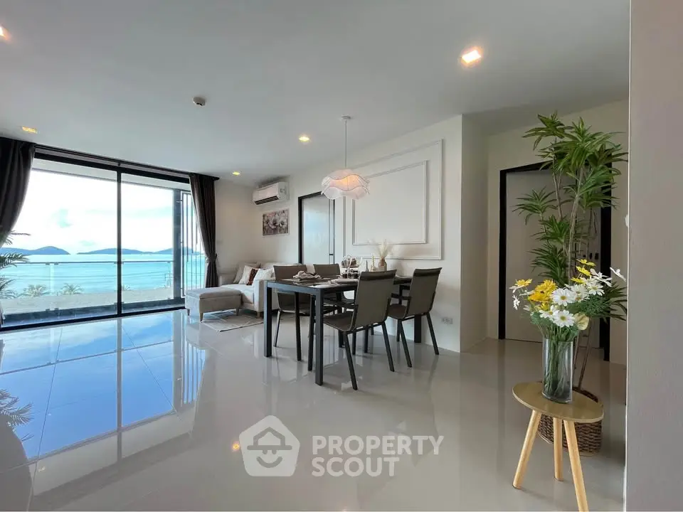 Stunning beachfront living room with panoramic ocean views and elegant dining area.