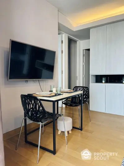 Modern dining area with wall-mounted TV and stylish chairs in a contemporary apartment