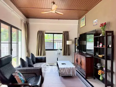 Charming living room with cozy seating, large TV, and natural light from windows.