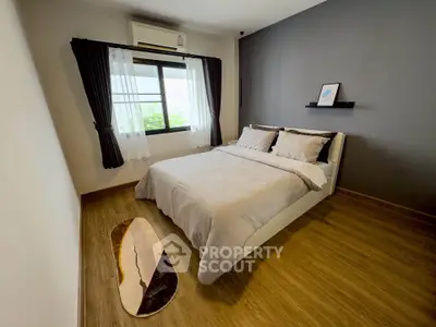 Modern bedroom with stylish decor and natural light, featuring a cozy bed and elegant wooden flooring.