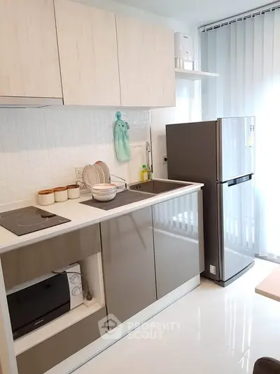 Modern kitchen with sleek cabinets, stainless steel fridge, and built-in appliances in a bright apartment.