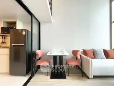 Modern living room with stylish furniture and open kitchen layout, featuring a cozy dining area and sleek appliances.