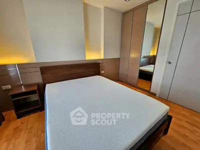 Modern bedroom with wooden flooring and built-in wardrobe in a stylish apartment.