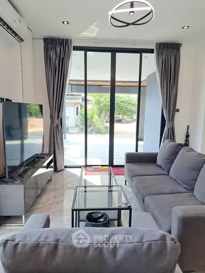 Modern living room with sleek furniture and large glass doors opening to a scenic view.