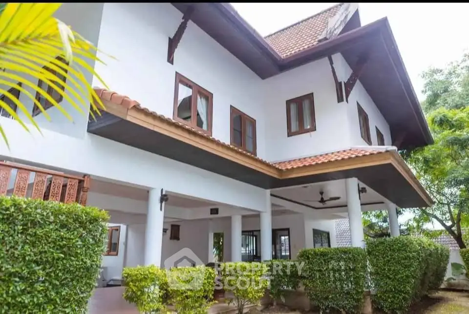 Charming two-story house with lush greenery and spacious covered patio, perfect for family living.