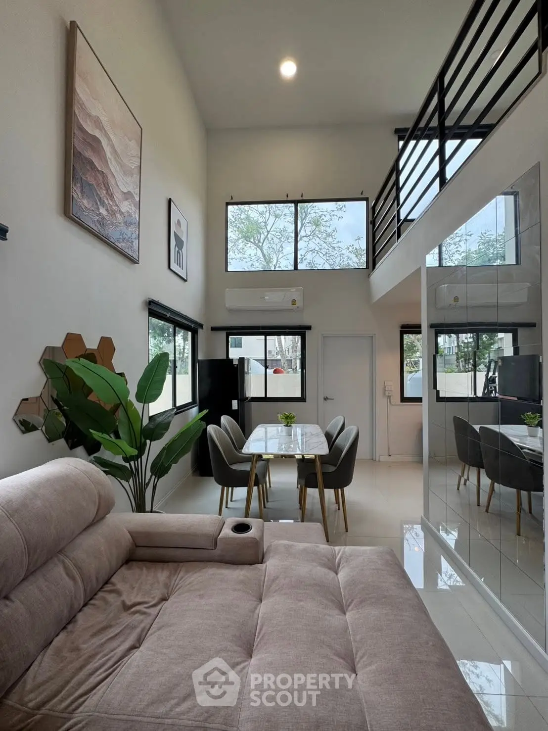 Modern living room with high ceiling, stylish decor, and large windows for natural light.