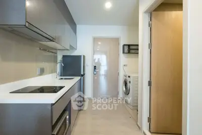 Modern kitchen with sleek appliances and washing machine in compact layout