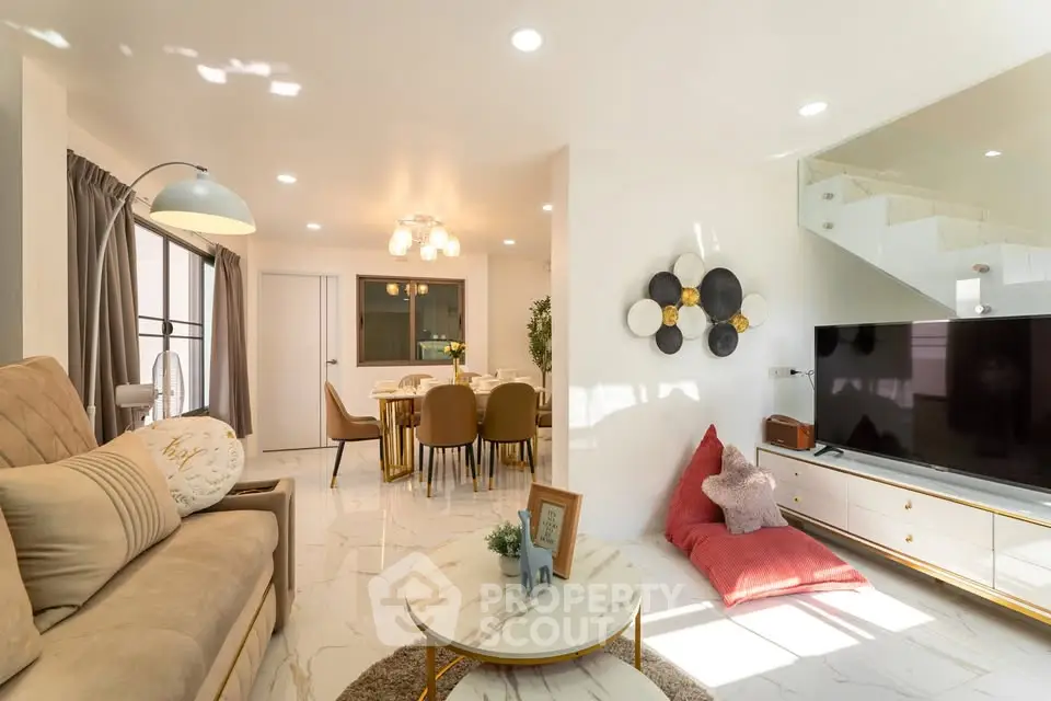 Spacious living room with modern decor and dining area, featuring elegant lighting and cozy seating.