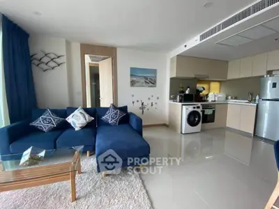 Modern living room with blue sofa, open kitchen, and washing machine, perfect for stylish urban living.