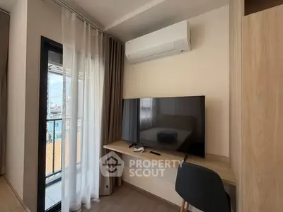 Modern study area with desk, chair, and wall-mounted TV near balcony.