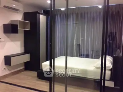 Modern bedroom with glass partition and sleek furnishings in a stylish apartment.