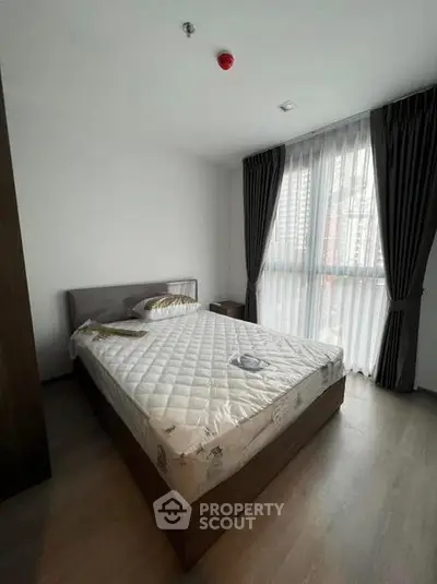 Modern bedroom with large window and stylish curtains in a contemporary apartment.