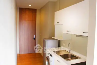 Compact kitchen with modern appliances and wooden flooring in a cozy apartment.
