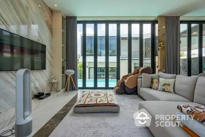 Luxurious living room with modern decor and direct pool access, featuring large windows for abundant natural light and a spacious layout perfect for entertaining.