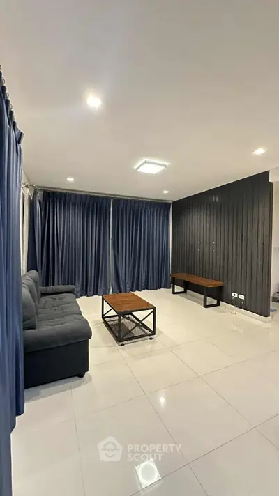 Modern living room with sleek black sofa and elegant curtains