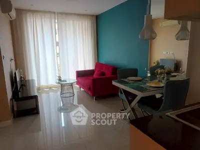 Modern living room with vibrant red sofa and dining area, featuring stylish lighting and large windows.