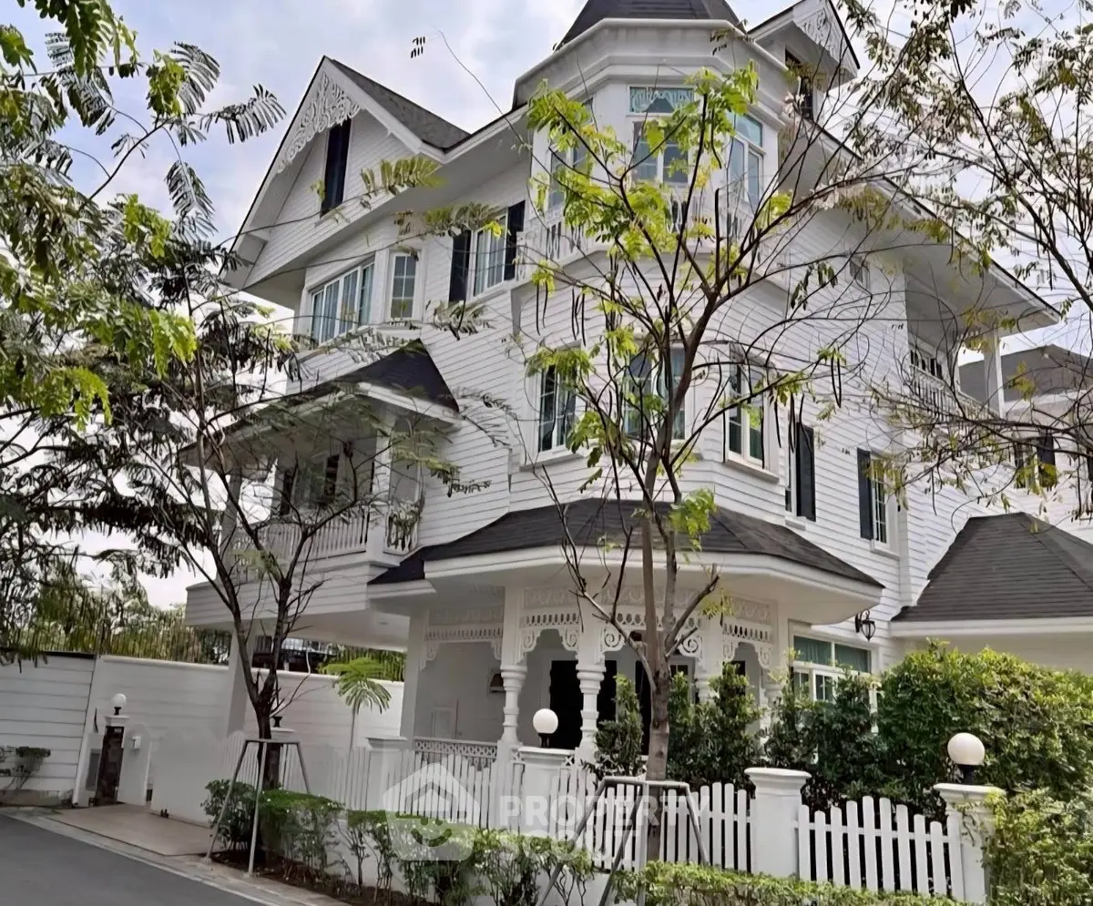 Stunning Victorian-style white house with lush greenery and charming picket fence