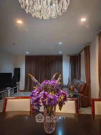 Elegant living room with chandelier, plush sofa, and vibrant floral centerpiece.