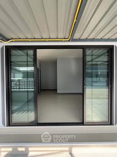 Modern sliding glass doors open to a spacious interior with sleek tile flooring, perfect for natural light.