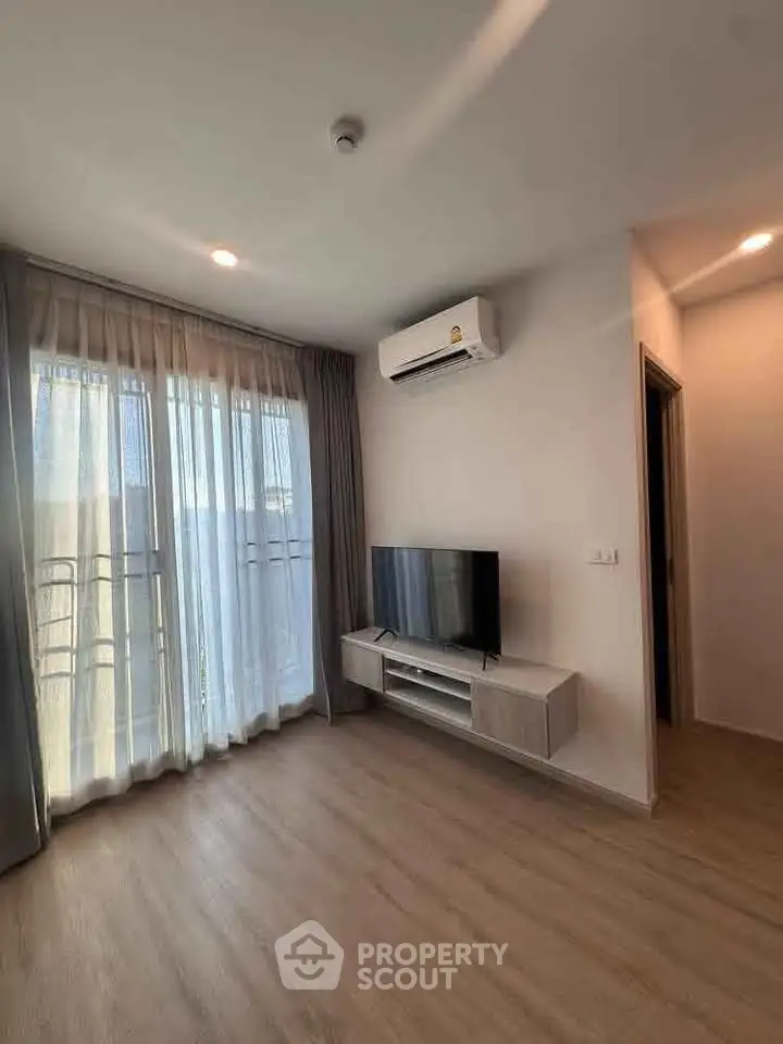 Modern living room with natural light, air conditioning, and sleek TV setup.