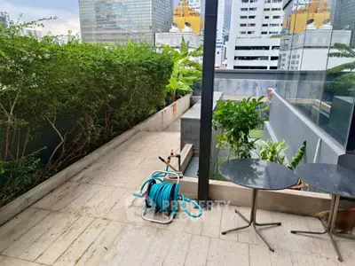 Spacious urban balcony with lush greenery and city views, perfect for relaxation and outdoor gatherings.