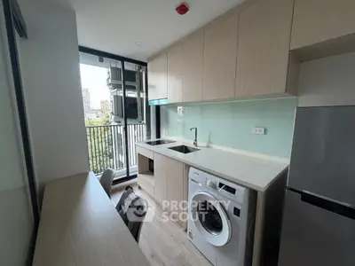 Modern kitchen with washing machine and balcony view in urban apartment