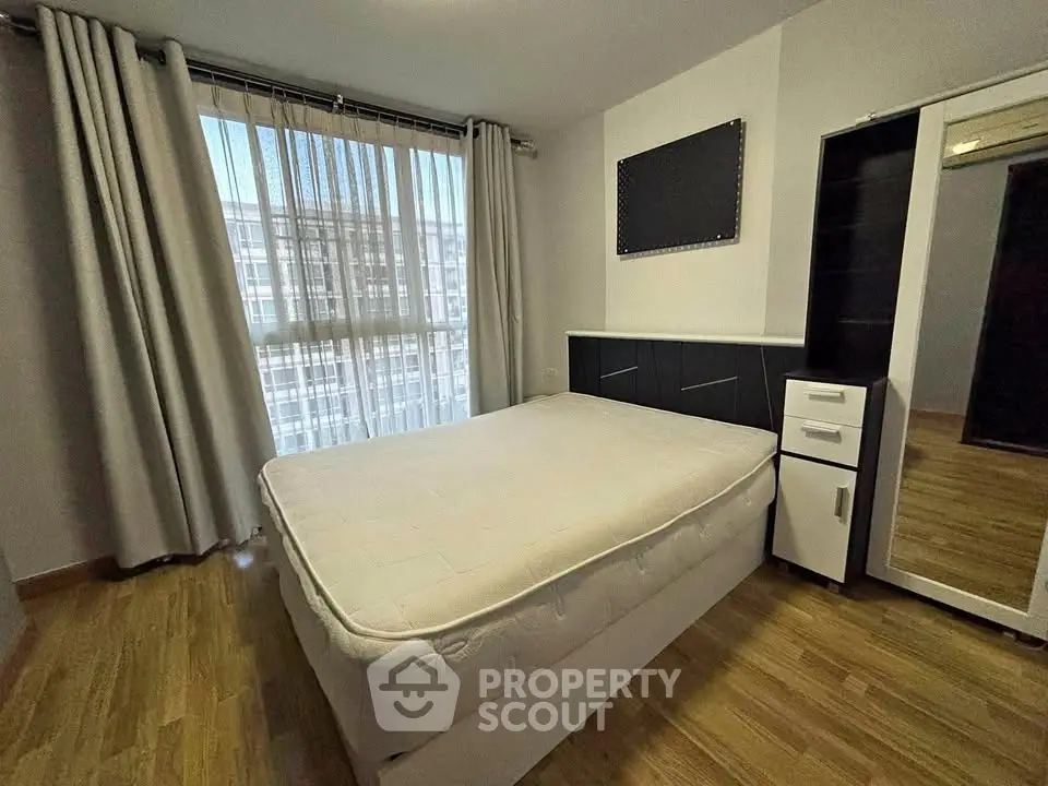 Spacious bedroom with large window and modern furnishings in a stylish apartment.