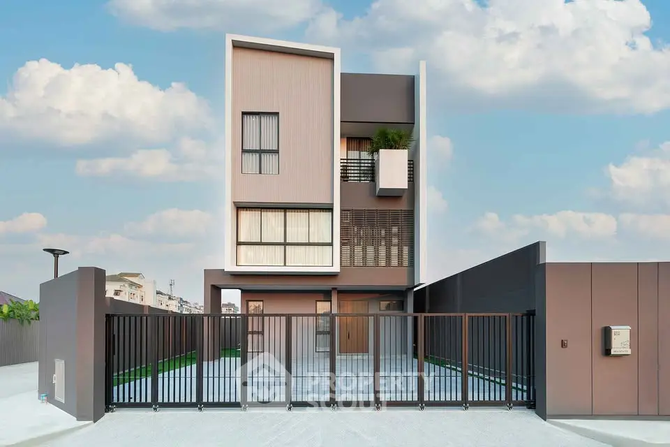 Modern architectural design of a contemporary three-story house with sleek facade and gated entrance.