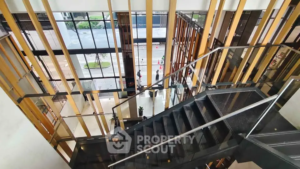 Modern building entrance with sleek staircase and glass walls, offering a stylish and inviting ambiance.