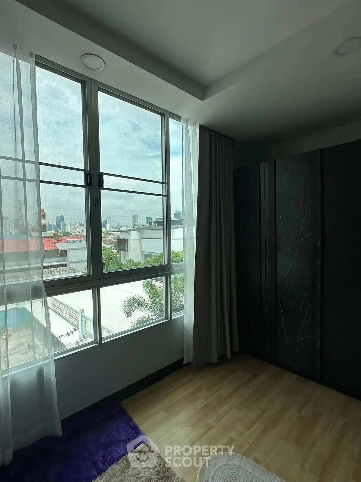 Spacious room with large windows offering a stunning city view, perfect for urban living.