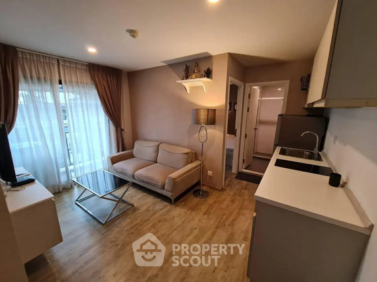 Modern living room with cozy sofa, glass coffee table, and open kitchen layout in stylish apartment.