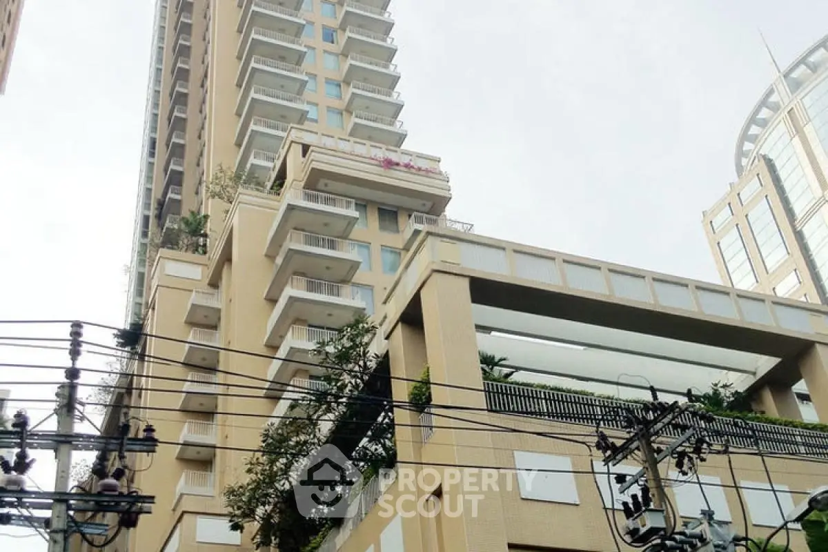Modern high-rise building with unique architectural design and spacious balconies in urban setting.