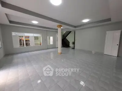 Spacious open-plan living area with tiled flooring and elegant column