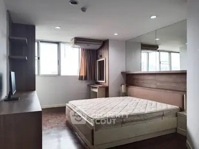 Spacious bedroom with large window and modern furnishings in urban apartment