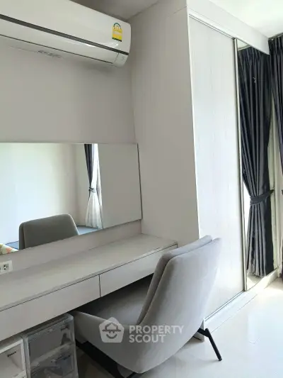 Modern study area with sleek desk, comfortable chair, and large mirror in a bright room.