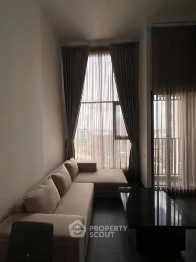 Modern living room with high ceilings and large windows, featuring a stylish sofa and elegant curtains.