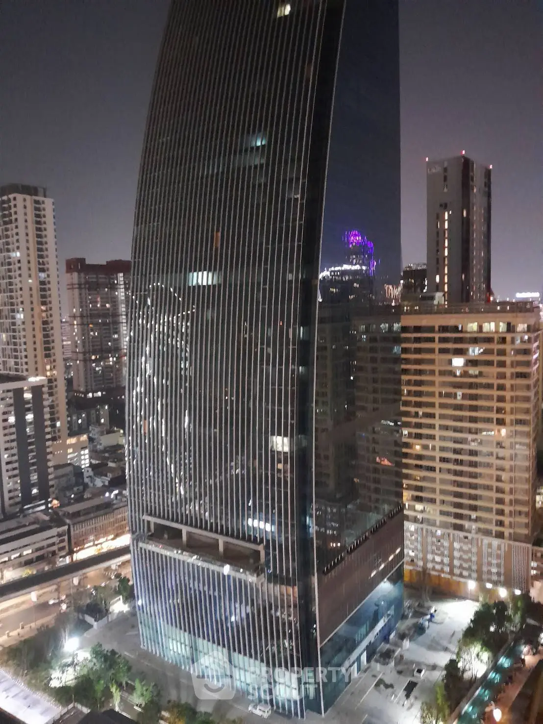 Stunning night view of modern skyscraper in bustling cityscape, showcasing architectural elegance and urban vibrancy.