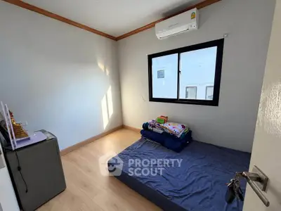 Minimalist bedroom with wooden flooring and air conditioning unit