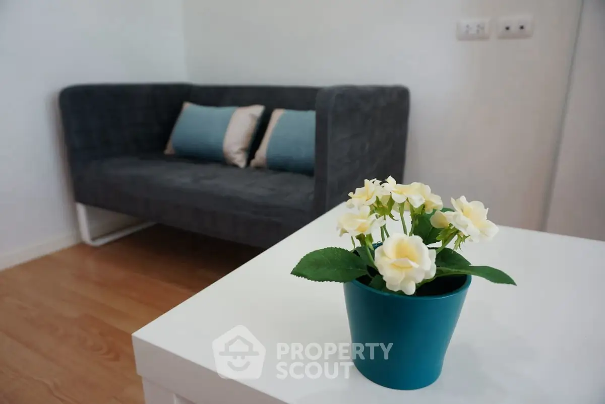 Cozy living room with modern gray sofa and decorative flower pot on white table