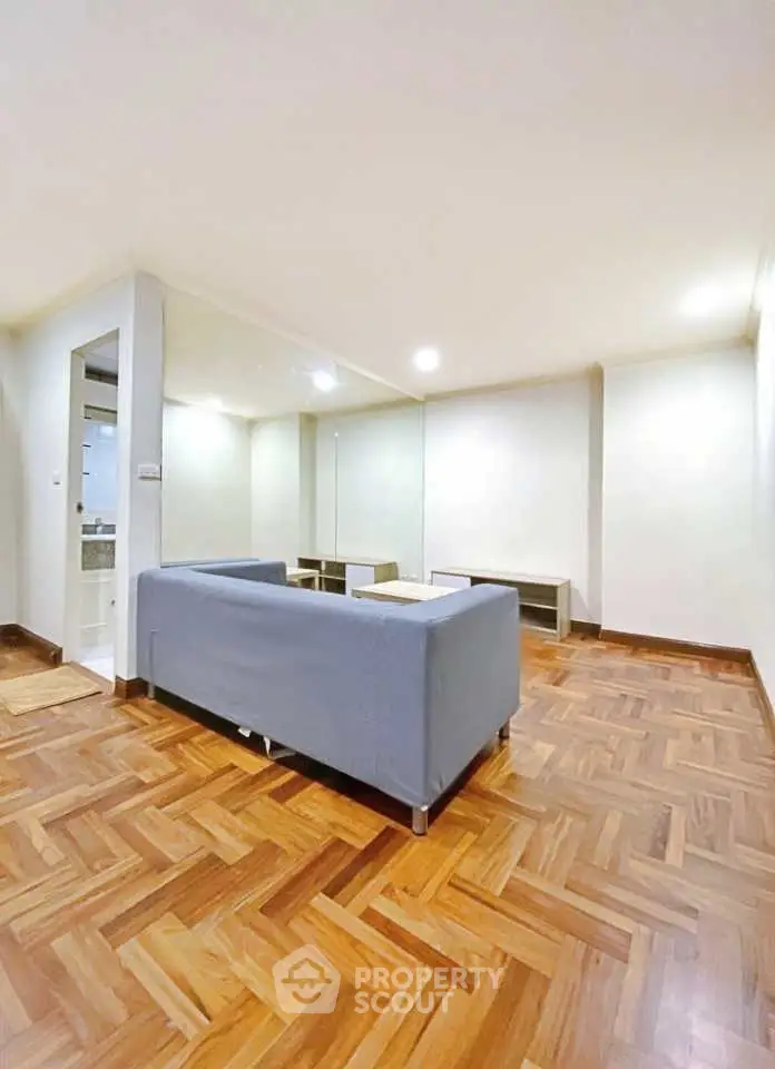 Spacious living room with elegant parquet flooring and modern sofa, perfect for relaxation and entertainment.