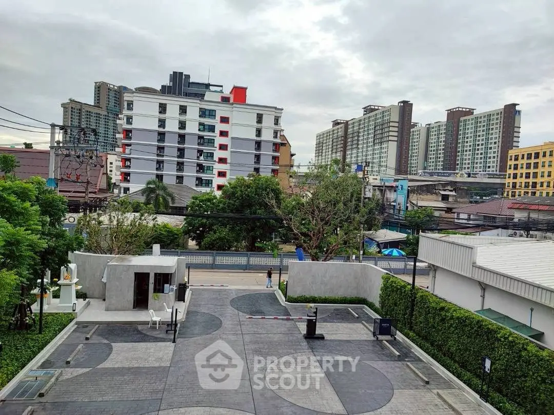 Modern urban apartment complex with landscaped entrance and city skyline view.