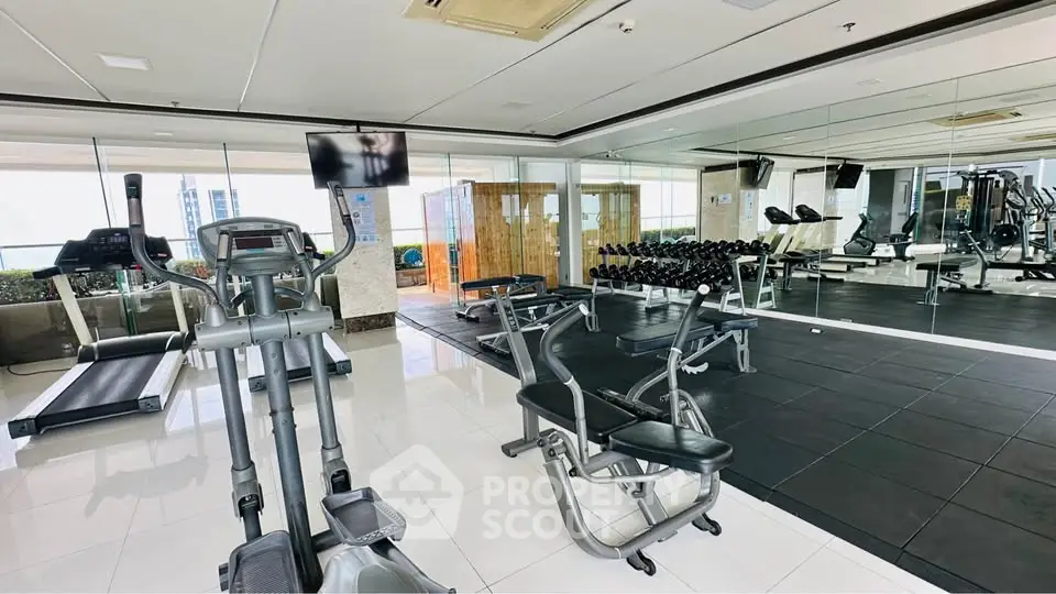 Spacious modern gym with state-of-the-art equipment and mirrored walls in luxury apartment complex.
