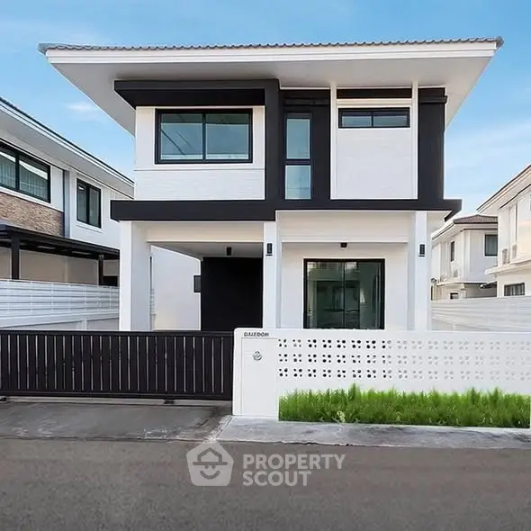 Modern two-story house with sleek design and spacious driveway in suburban neighborhood.