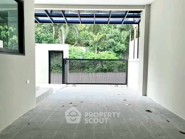 Spacious modern garage with sleek gate and lush greenery view.